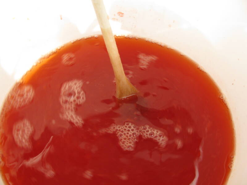 A fermenter of strawberry juice being stirred.