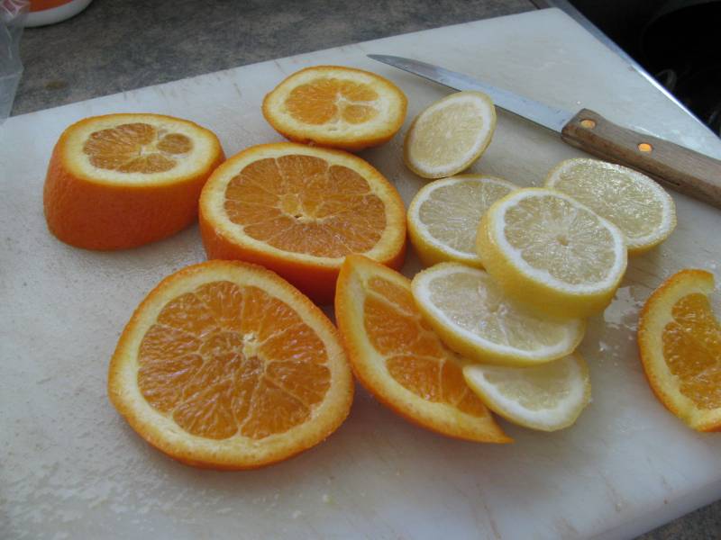 Orange slices and lemon slices sit on a cutting board.