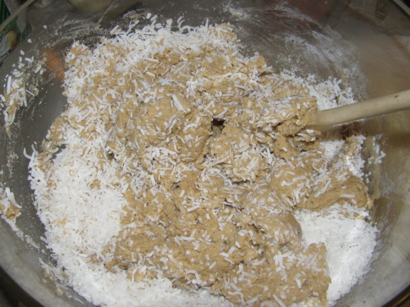 Flaked coconut being mixed into cookie dough.