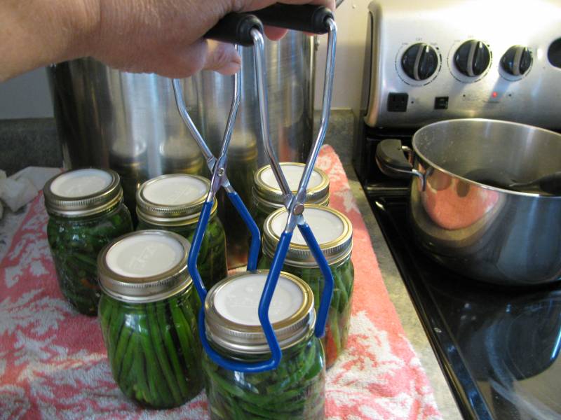 Picking up a mason jar with tongs.