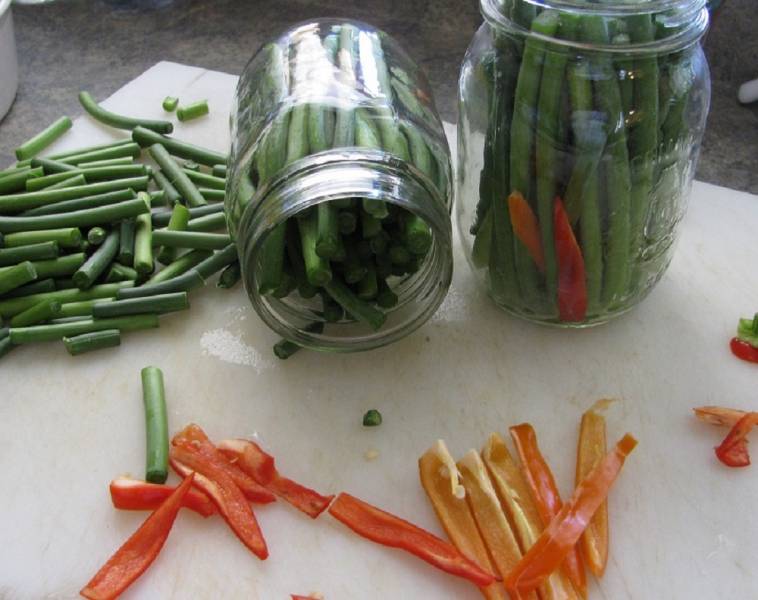 Two mason jars fille with garlic scapes.