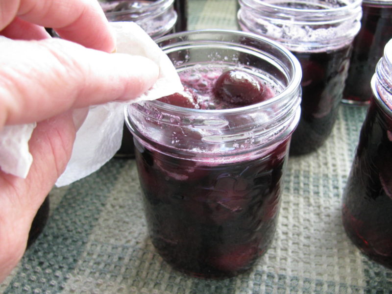 Wiping the rims of jars with a paper towel before sealing.