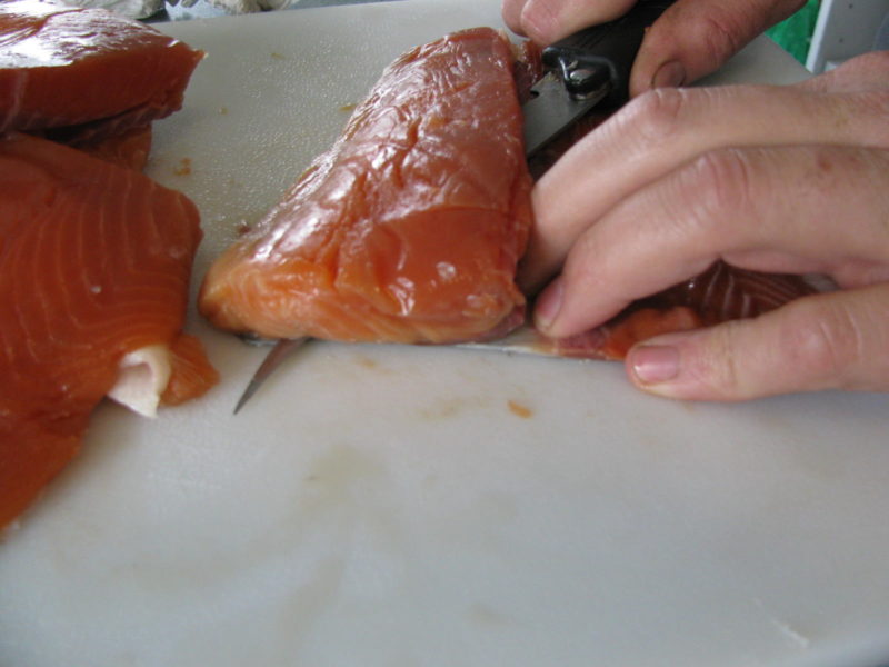 Skinning the salmon meat away from the skin.