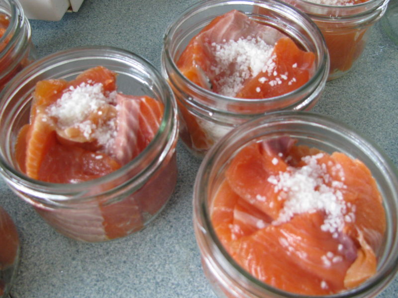Salt sprinkled on top of salmon in canning jars.