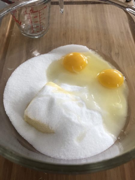 Butter, sugar, and eggs in a clear bowl.
