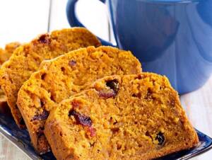 Baked Pumpkin Cranberry Bread on a table with coffee