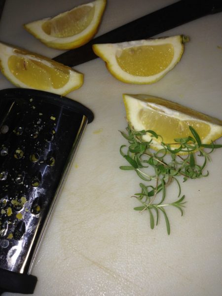 Lemon wedges and rosemary on a cutting board.