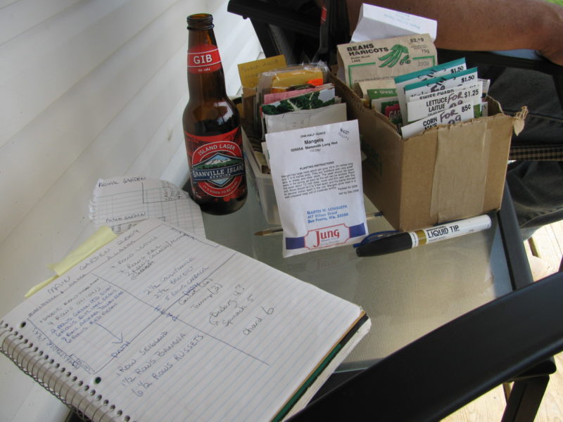 Written garden plan on a table with lots of seed packages.