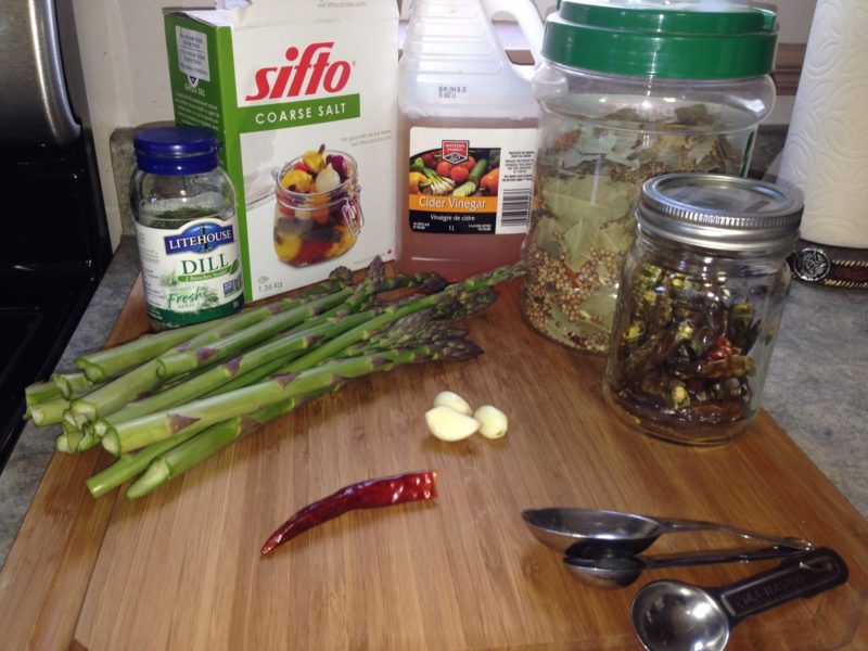 Ingredients for pickled asparagus on a cutting board.