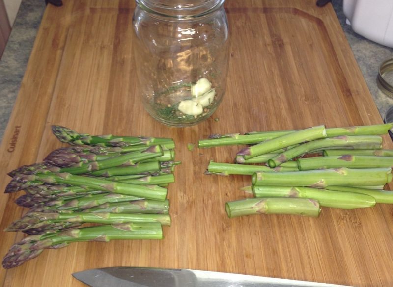 Asparagus spears cut in half on a cutting board.