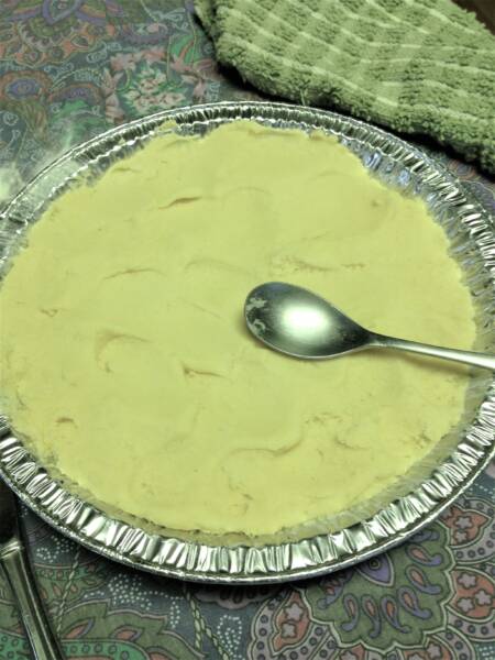 Smoothing the Boterkoek with the back of a spoon.