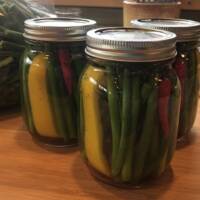 Pickled Garlic Scapes in Canning Jars on wood counter