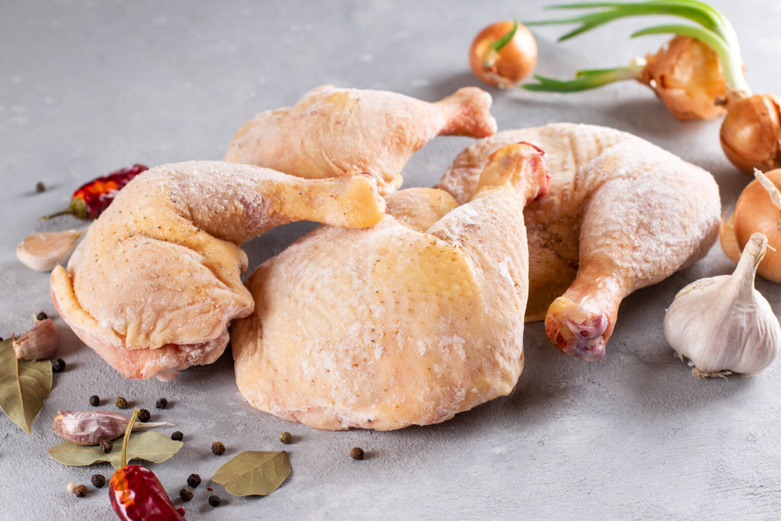 Frozen chicken pieces on a counter for defrosting.