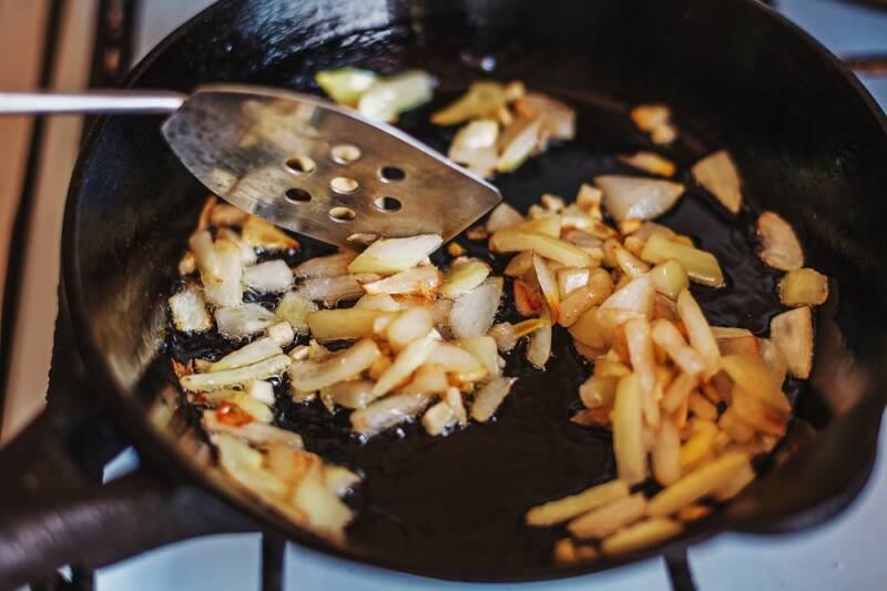 Roasting garlic cloves in a pan on the stove.