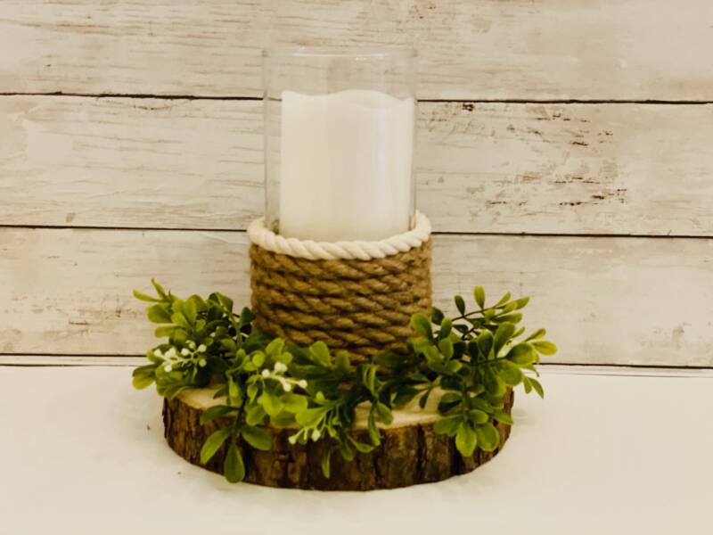 Farmhouse rope candle holder with holly and berries on a slab of wood.