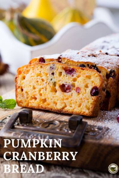 Pumpkin Cranberry bread with a light glaze sits on a wood serving tray.