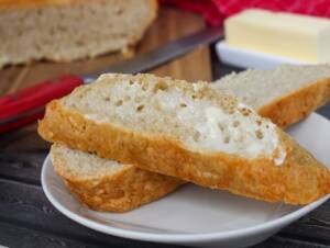 Warm Dutch Oven no knead bread with melted butter sitting on a white plate