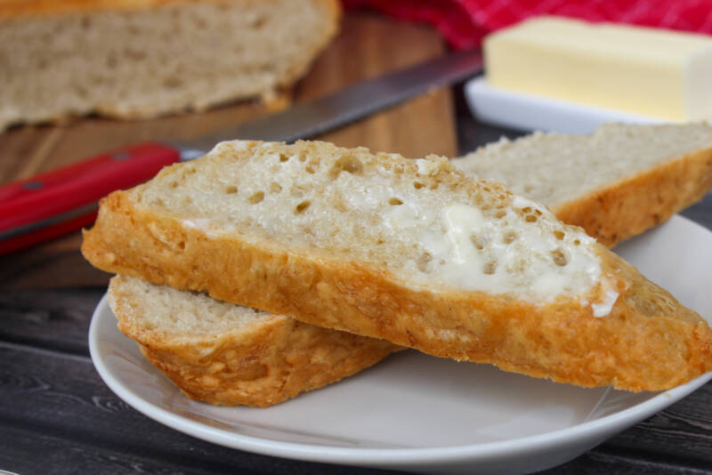 Dutch Oven No Knead bread with melted butter on it sitting on a plate
