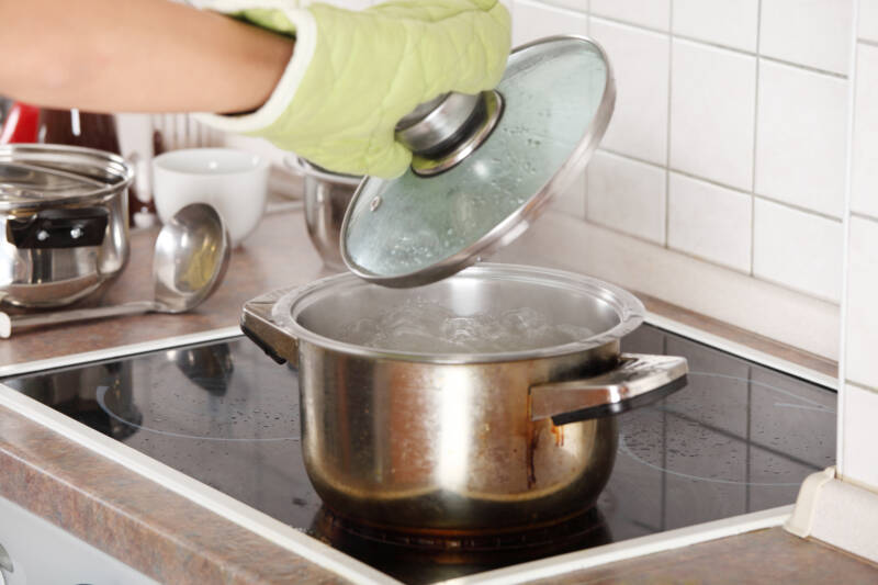 Lifiting a lid off a pot of boiling water.