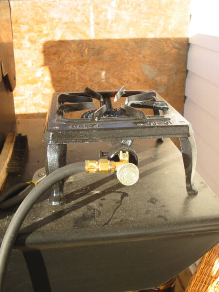 A propane burner sitting on a dark surface.