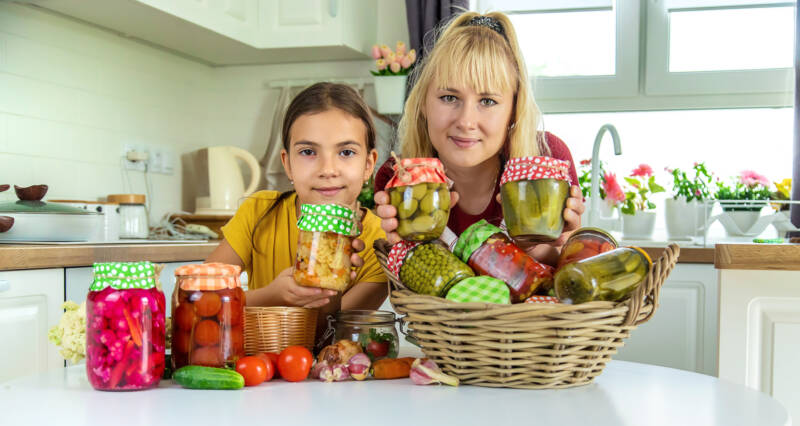 A woman and a girl holding cans of foods.