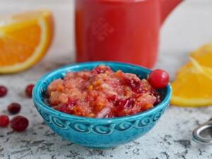 Cranberry Orange Relish in a blue bowl with single cranberry for garnish