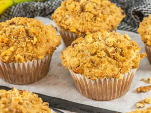 Jumbo Banana Muffins with nuts and streusel topping sit on a cooling sheet.