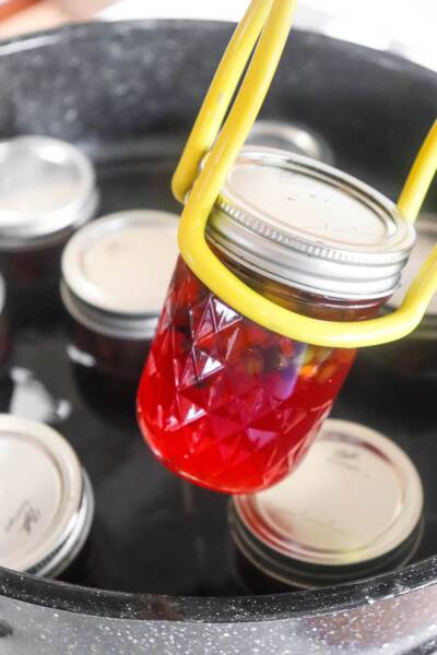 Using tongs to add filled jars to the water bath canner.