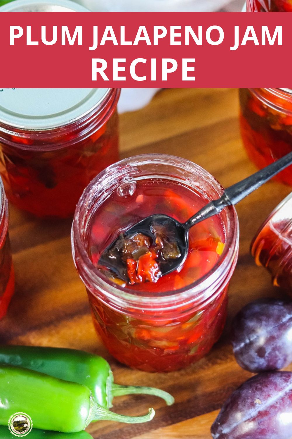 Plum Jalapeno Jam jelly in a mason jar that is opened. Beside are full sealed canning jars.